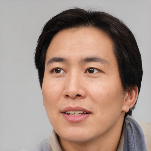 Joyful asian adult male with medium  brown hair and brown eyes