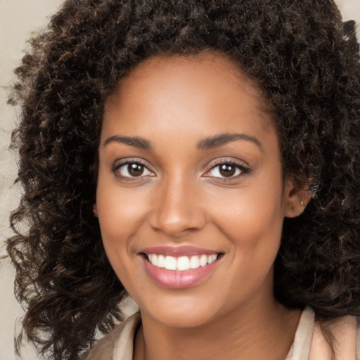 Joyful black young-adult female with long  brown hair and brown eyes