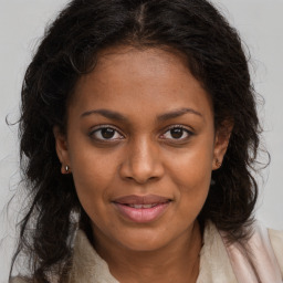 Joyful black young-adult female with long  brown hair and brown eyes