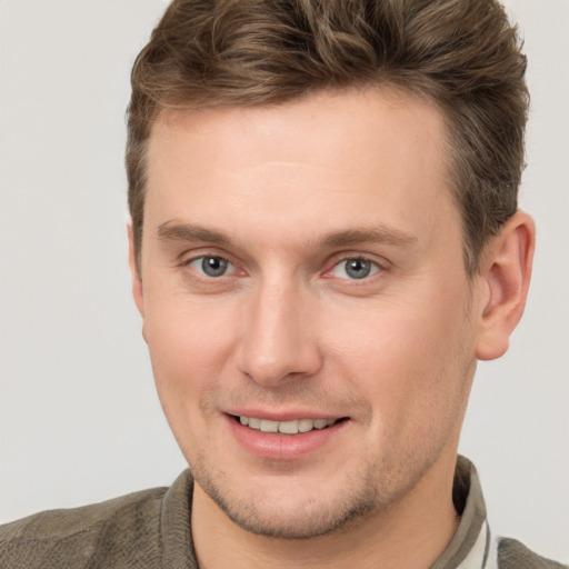 Joyful white young-adult male with short  brown hair and grey eyes