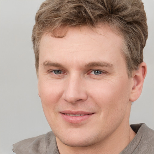 Joyful white young-adult male with short  brown hair and grey eyes