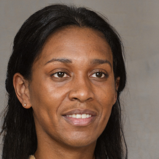 Joyful black adult female with long  brown hair and brown eyes