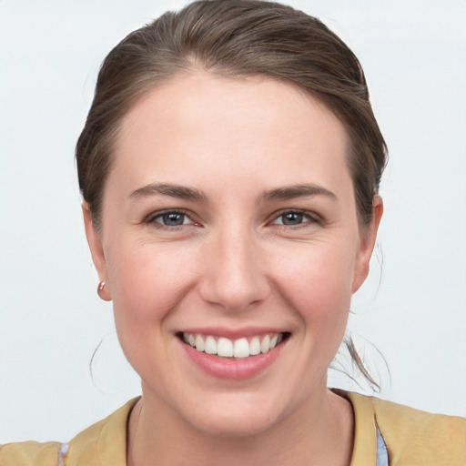 Joyful white young-adult female with medium  brown hair and grey eyes