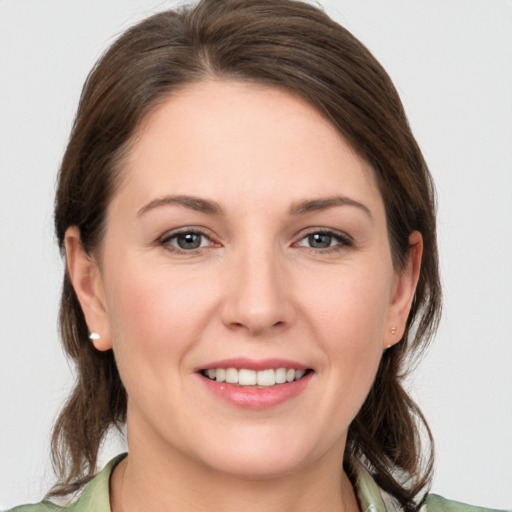 Joyful white young-adult female with medium  brown hair and grey eyes