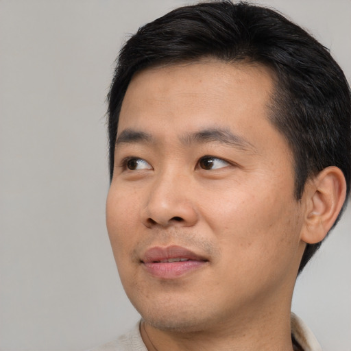 Joyful asian young-adult male with short  brown hair and brown eyes