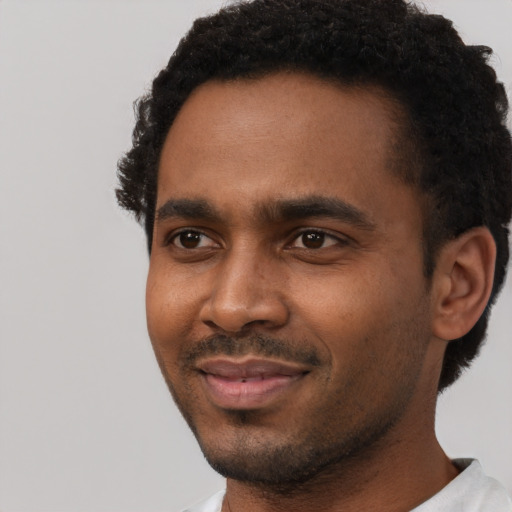 Joyful black young-adult male with short  black hair and brown eyes