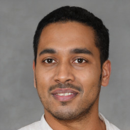 Joyful latino young-adult male with short  black hair and brown eyes