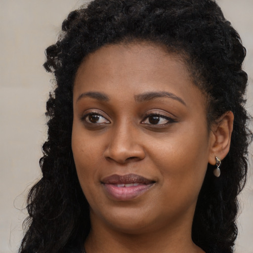 Joyful black young-adult female with long  brown hair and brown eyes