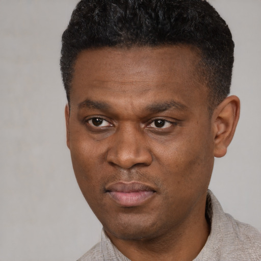 Joyful black young-adult male with short  black hair and brown eyes