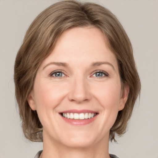 Joyful white adult female with medium  brown hair and grey eyes