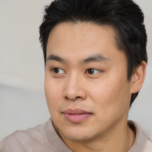 Joyful asian young-adult male with short  brown hair and brown eyes
