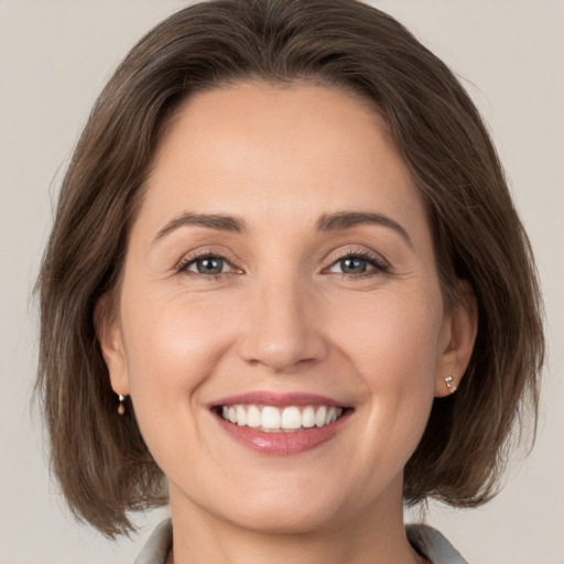 Joyful white young-adult female with medium  brown hair and grey eyes