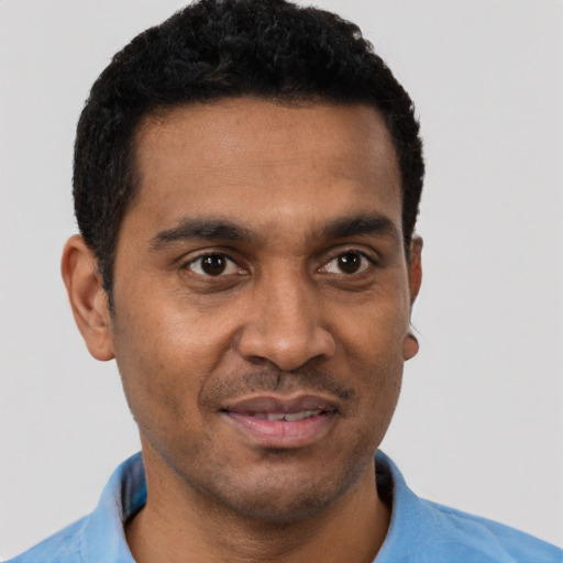 Joyful black young-adult male with short  brown hair and brown eyes