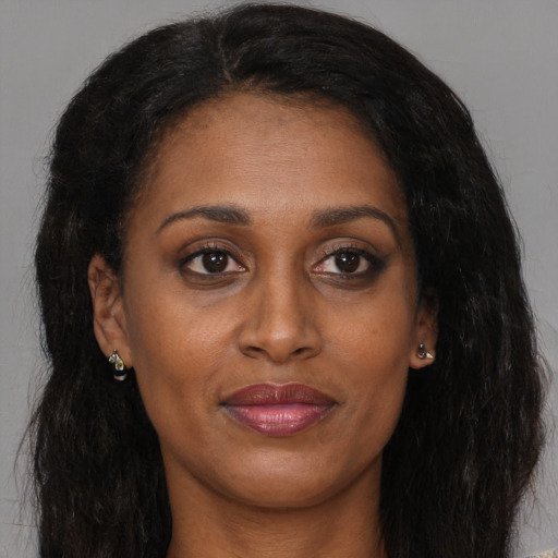 Joyful black adult female with long  brown hair and brown eyes