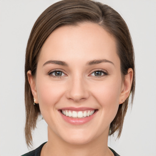 Joyful white young-adult female with medium  brown hair and grey eyes