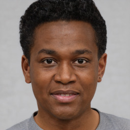 Joyful black young-adult male with short  black hair and brown eyes