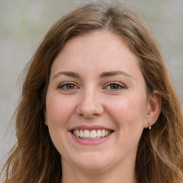 Joyful white adult female with long  brown hair and grey eyes