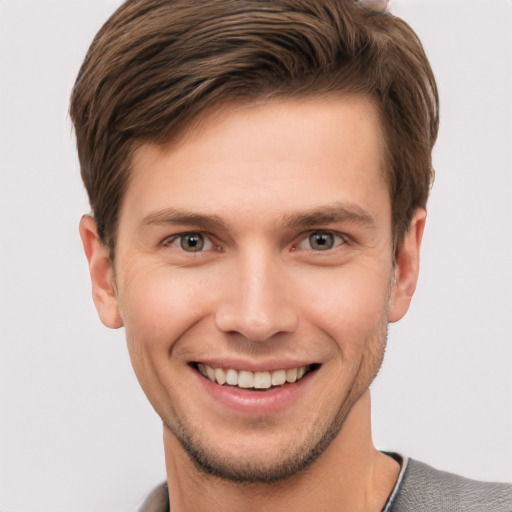 Joyful white young-adult male with short  brown hair and grey eyes