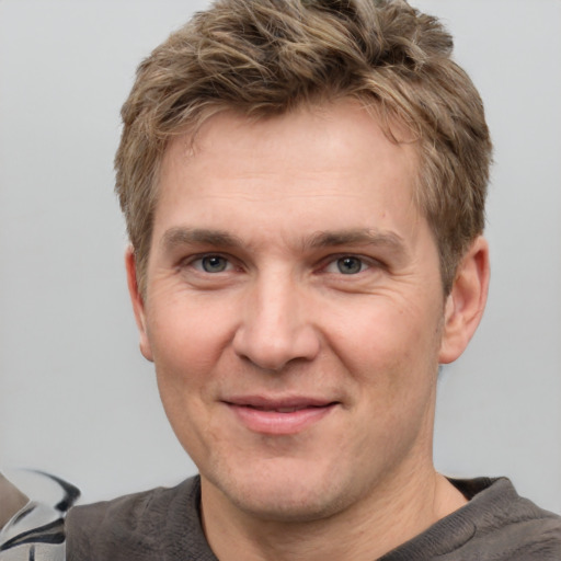 Joyful white adult male with short  brown hair and grey eyes