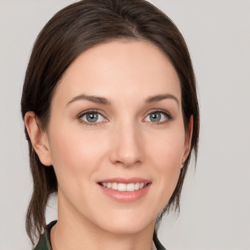 Joyful white young-adult female with medium  brown hair and grey eyes