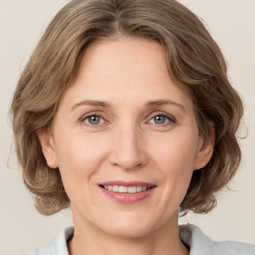 Joyful white adult female with medium  brown hair and grey eyes