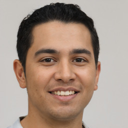 Joyful latino young-adult male with short  brown hair and brown eyes