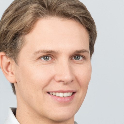 Joyful white young-adult male with short  brown hair and grey eyes