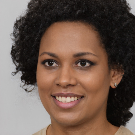Joyful black young-adult female with long  brown hair and brown eyes