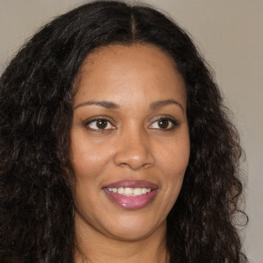 Joyful black young-adult female with long  brown hair and brown eyes