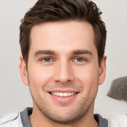 Joyful white young-adult male with short  brown hair and grey eyes