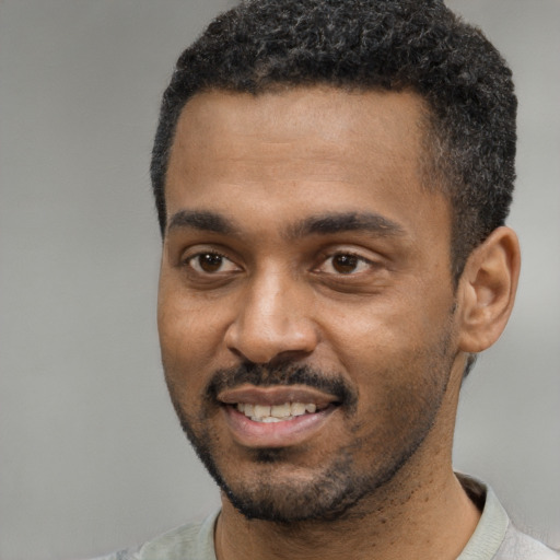 Joyful black young-adult male with short  black hair and brown eyes