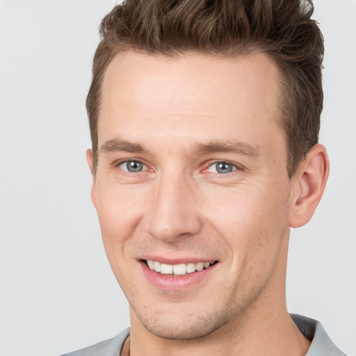 Joyful white young-adult male with short  brown hair and grey eyes