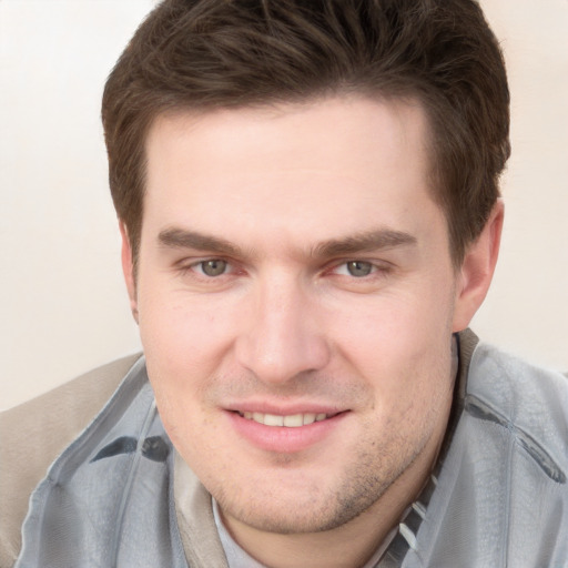 Joyful white young-adult male with short  brown hair and grey eyes