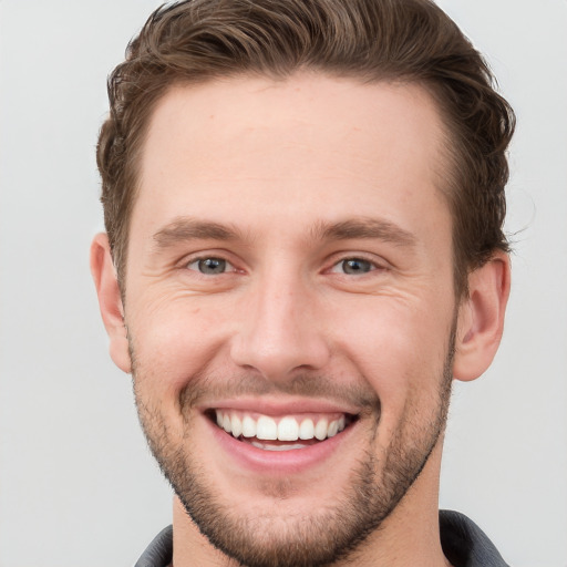 Joyful white young-adult male with short  brown hair and grey eyes