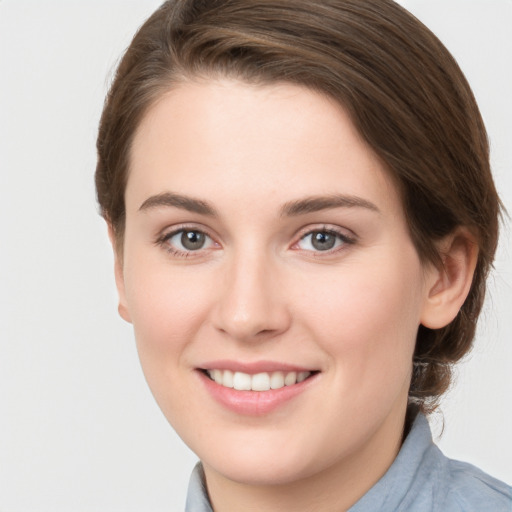 Joyful white young-adult female with medium  brown hair and grey eyes