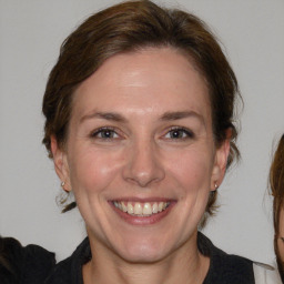 Joyful white adult female with medium  brown hair and grey eyes