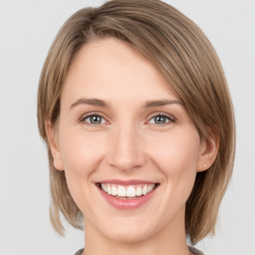 Joyful white young-adult female with medium  brown hair and grey eyes