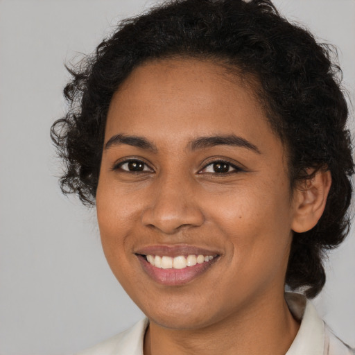 Joyful black young-adult female with long  brown hair and brown eyes