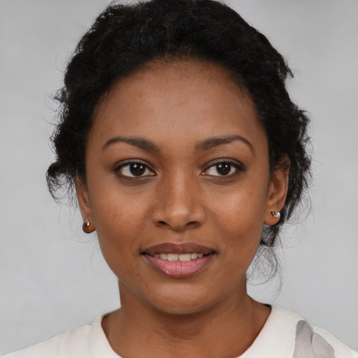 Joyful black young-adult female with short  black hair and brown eyes