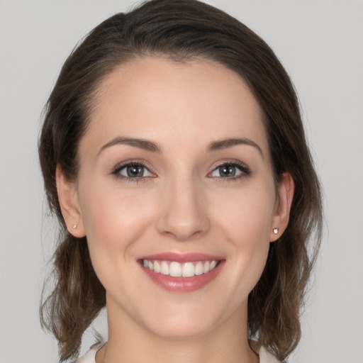 Joyful white young-adult female with medium  brown hair and grey eyes