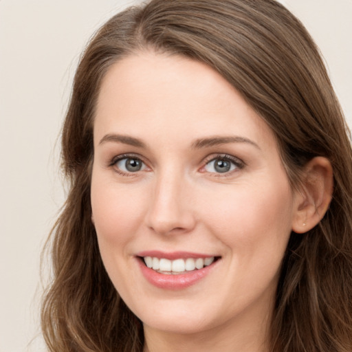 Joyful white young-adult female with long  brown hair and blue eyes