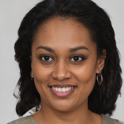 Joyful black young-adult female with long  brown hair and brown eyes