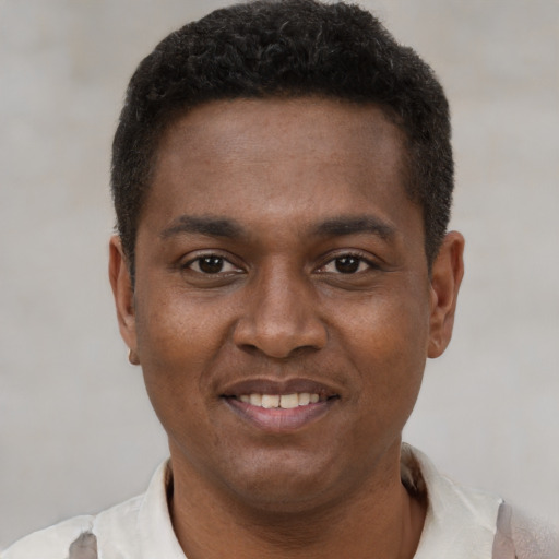 Joyful black young-adult male with short  brown hair and brown eyes