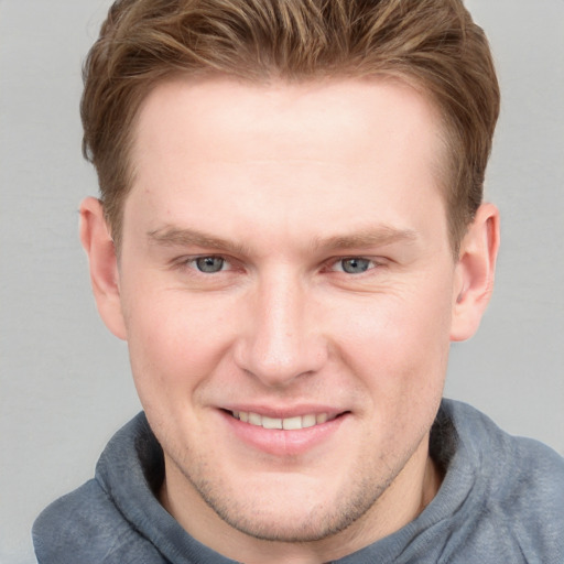 Joyful white young-adult male with short  brown hair and blue eyes