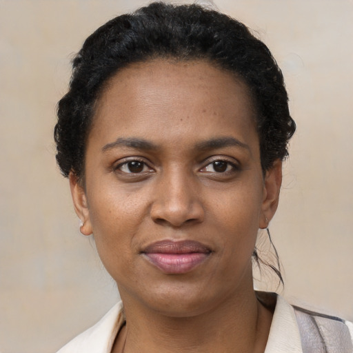 Joyful black young-adult female with short  black hair and brown eyes
