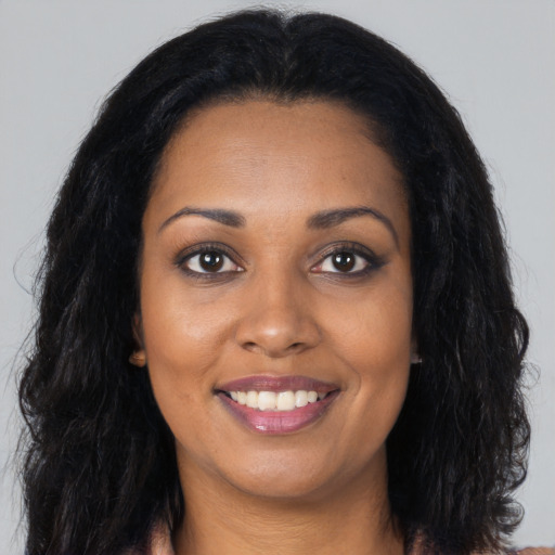Joyful black young-adult female with long  black hair and brown eyes