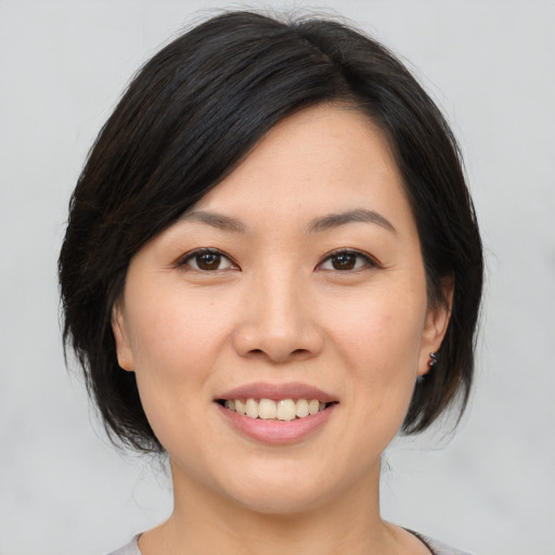 Joyful asian young-adult female with medium  brown hair and brown eyes
