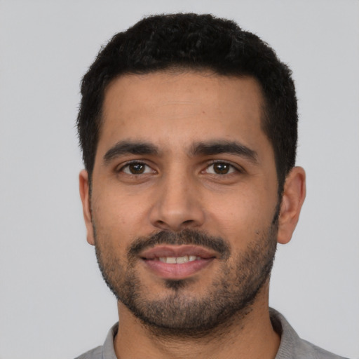 Joyful latino young-adult male with short  black hair and brown eyes