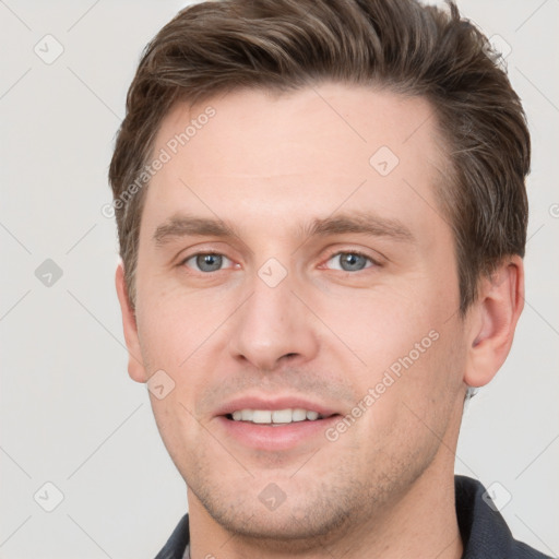 Joyful white young-adult male with short  brown hair and grey eyes