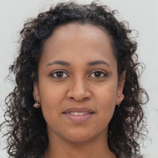 Joyful black young-adult female with long  brown hair and brown eyes